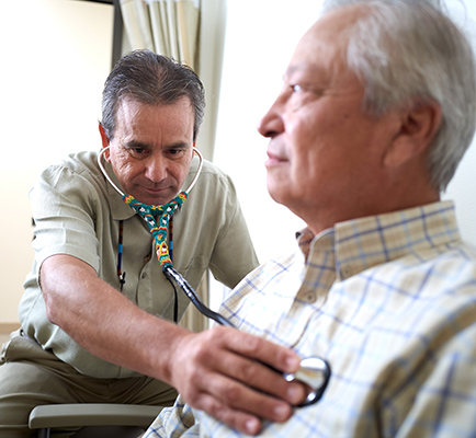 Health care worker uses stethoscope on older person