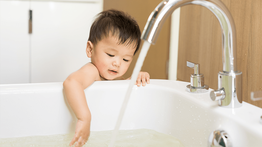 child putting hand in bathtub with water running